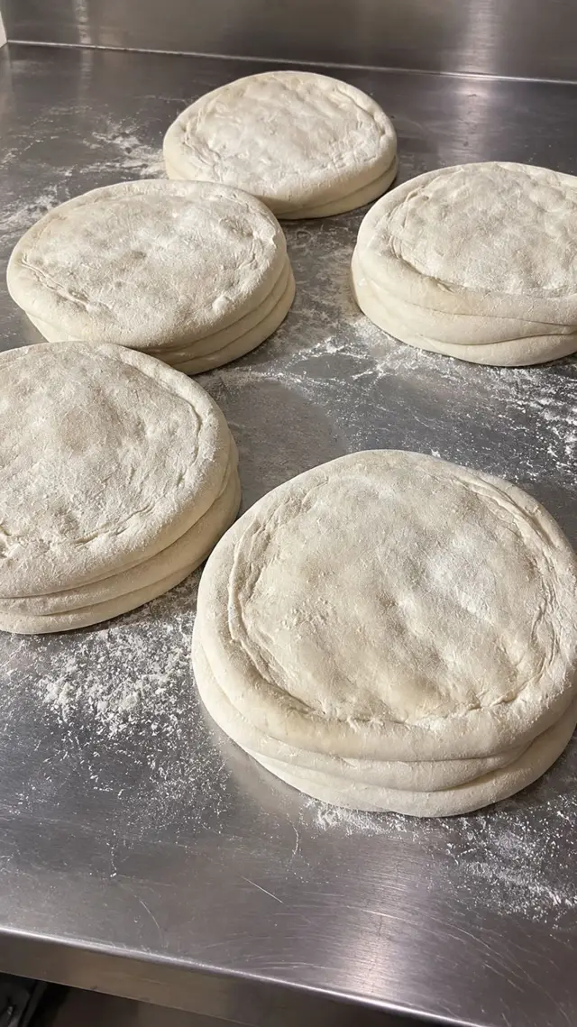 Discos de pizza estirados sobre mesa de acero