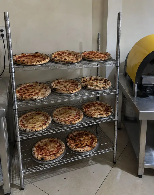 Pizzas enfriándose en estantería de acero