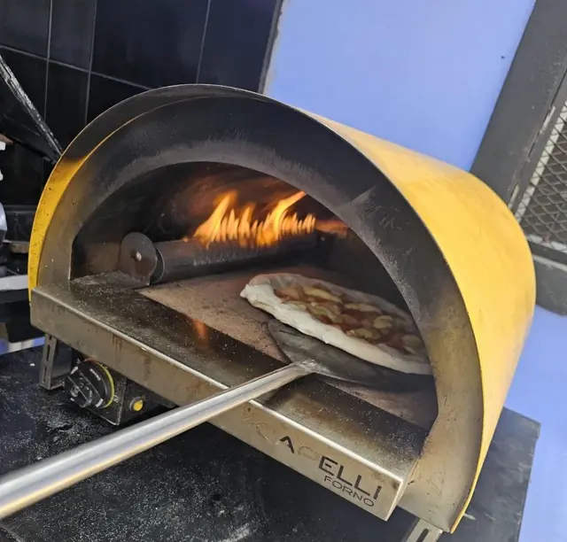 Pizza en la pala frente al horno